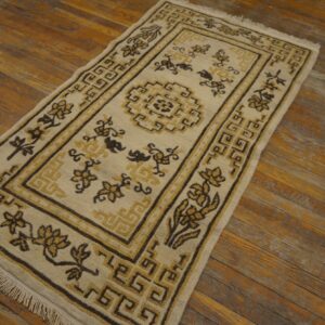 Beige runner with geometric borders and floral designs in dark brown and gold on wood planks.