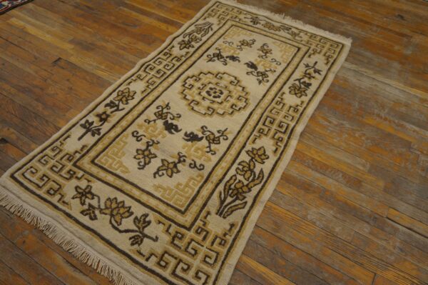 Beige runner with geometric borders and floral designs in dark brown and gold on wood planks.