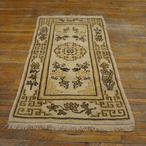 Cream rug with brown and gold geometric and floral patterns shown on rustic distressed wood flooring.