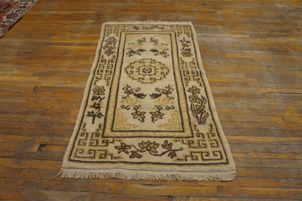 Cream rug with brown and gold geometric and floral patterns shown on rustic distressed wood flooring.