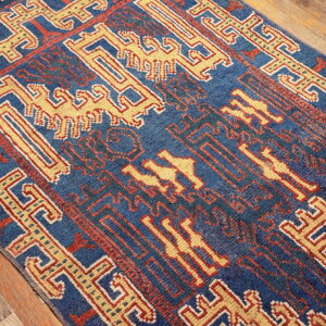 Deep blue rug with contrasting yellow and red tribal motifs sits on weathered wood flooring.