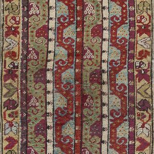 Vertical striped rug in red, olive green, purple, and tan with repeating geometric and scrolling patterns.