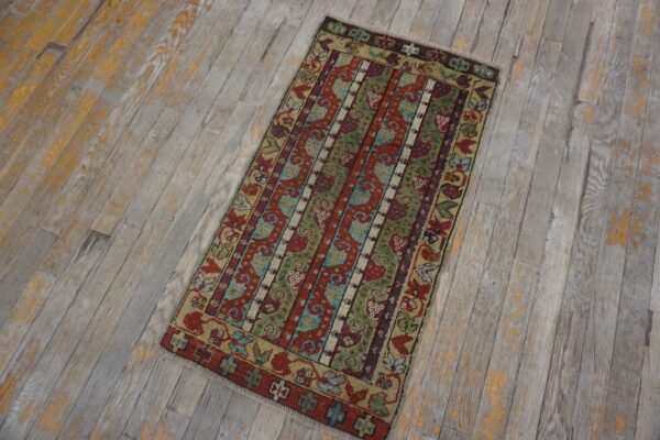A colorful tribal rug with red, green, and blue stripes rests on weathered gray wood flooring.