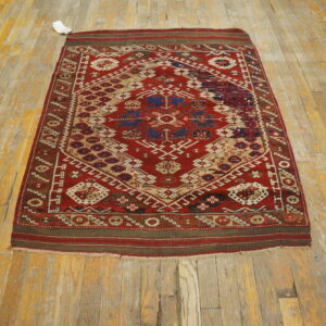 Geometric red rug featuring medallions in navy blue and beige lies on distressed wood flooring.