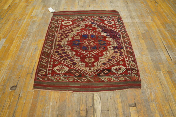 Geometric red rug featuring medallions in navy blue and beige lies on distressed wood flooring.