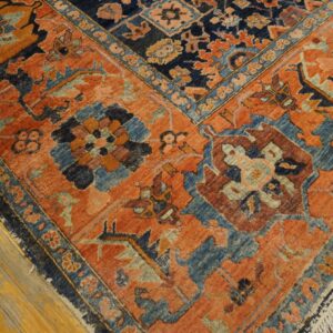 Burnt orange and dark blue traditional rug with geometric floral motifs on light wood floors.