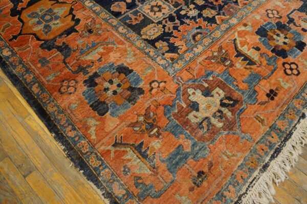 Burnt orange and dark blue traditional rug with geometric floral motifs on light wood floors.