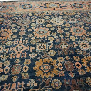 Traditional dark blue rug with intricate apricot and gold floral and geometric patterns and a wide light border.