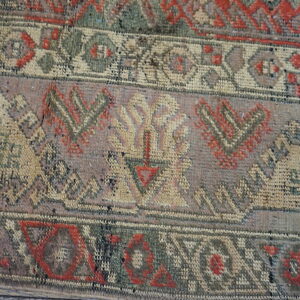 Close-up showing woven bands with detailed geometric patterns in faded red, green, tan, and gray colors.