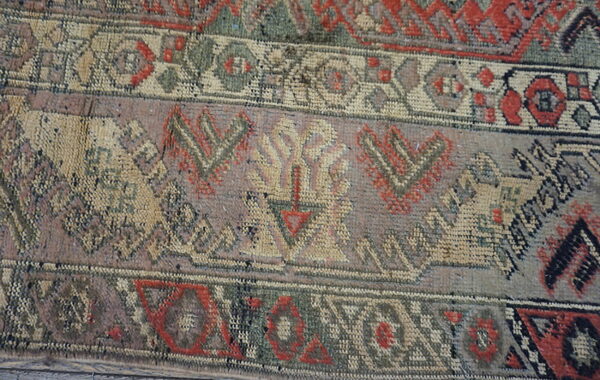 Close-up showing woven bands with detailed geometric patterns in faded red, green, tan, and gray colors.