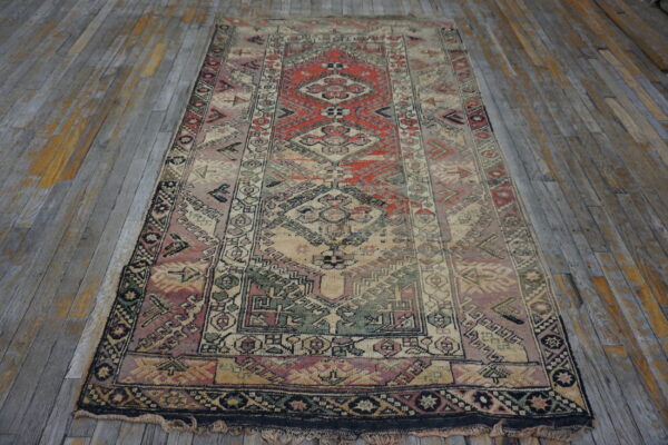Distressed geometric runner rug featuring muted red, beige, and green on gray wood planks.