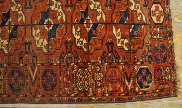 Deep reddish-brown rug with geometric tribal patterns in navy blue and cream over light wood flooring.