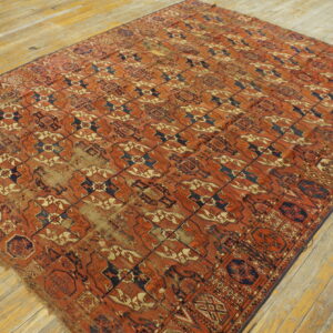 Large rectangular rug featuring a rust, navy, and tan repeating geometric pattern on wide wood planks.