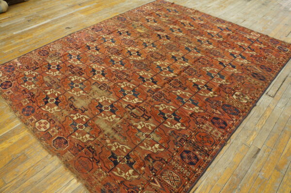 Large rectangular rug featuring a rust, navy, and tan repeating geometric pattern on wide wood planks.
