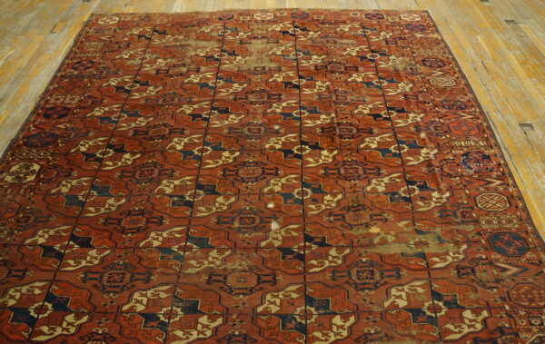 Distressed terracotta and navy geometric rug with repeating patterns rests on wide plank wooden flooring.