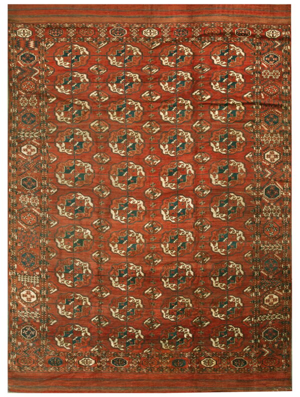 A rust-red geometric rug features repeating dark teal, cream, and brown gul motifs in the central field.