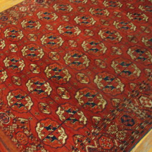 A large red rug with repeating navy and cream geometric patterns rests on light wood floors.