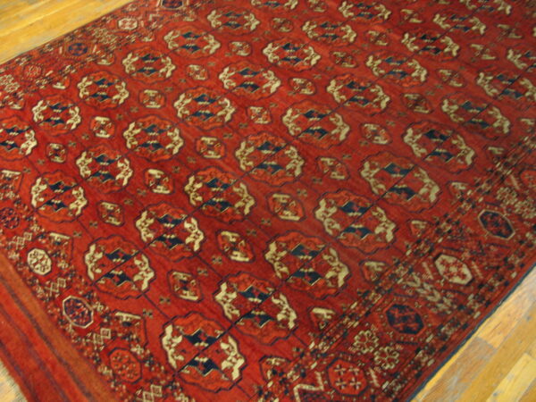 A large red rug with repeating navy and cream geometric patterns rests on light wood floors.