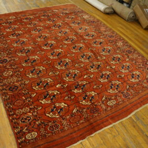 Red geometric rug with navy and tan accents displayed on light wood plank flooring.