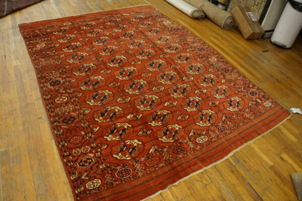 Red geometric rug with navy and tan accents displayed on light wood plank flooring.