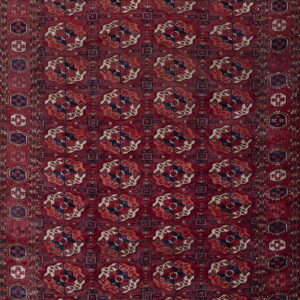 A burgundy low-pile rug featuring repeating navy, rust, and cream geometric tribal motifs.