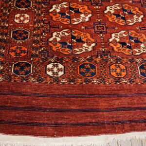 Rust-colored rug features contrasting navy and cream geometric medallions on light wood floorboards.