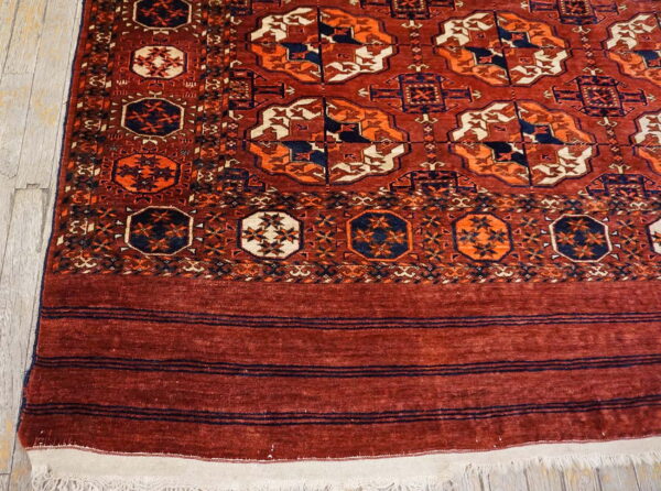 Rust-colored rug features contrasting navy and cream geometric medallions on light wood floorboards.
