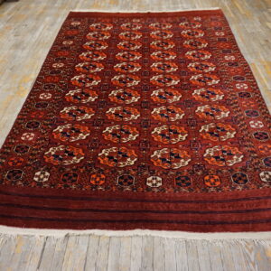 Burgundy rug featuring repeated orange, cream, and navy geometric patterns on distressed wood planks.