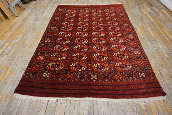 Burgundy rug featuring repeated orange, cream, and navy geometric patterns on distressed wood planks.