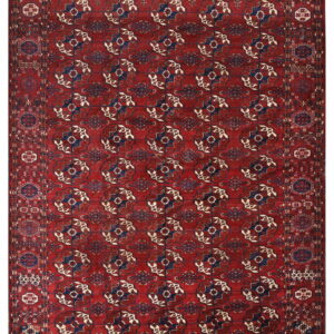 A richly patterned rug with a deep red field and repeating navy blue and cream geometric medallions.