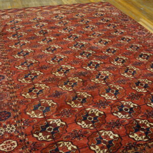Terracotta and navy rug with repeated geometric medallions rests on distressed wood planks.