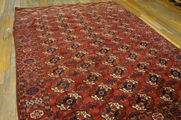 Terracotta and navy rug with repeated geometric medallions rests on distressed wood planks.