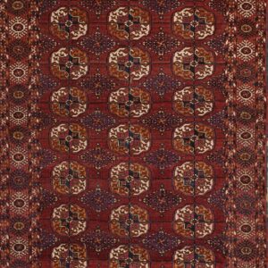 Low-pile rug with a deep red field and repeating geometric guls in rust, cream, and blue.
