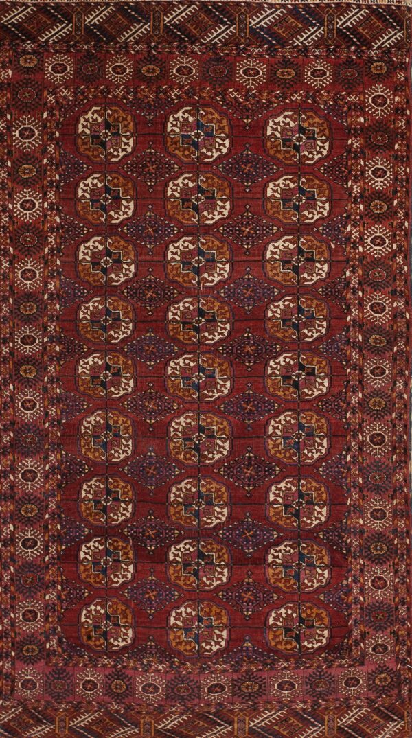 Low-pile rug with a deep red field and repeating geometric guls in rust, cream, and blue.