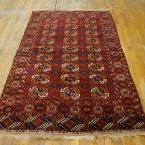 Red rug with repeating geometric guls in blue, gold, and white rests on light wood floors.