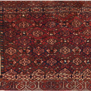 Red rug with a dense geometric field pattern and elaborate borders in navy, black, and cream colors.