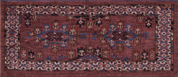 Low-pile rug with a deep red field and geometric tribal patterns in blue, tan, and black.