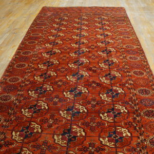 Long reddish-orange runner rug with geometric medallions in navy and cream on light wood flooring.