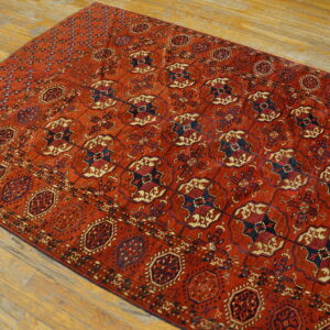 A rust-colored rug with repeating navy and cream geometric patterns rests on light hardwood plank flooring.
