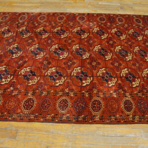 Terracotta rug featuring repeating navy blue and cream geometric medallions on light plank wood floor.