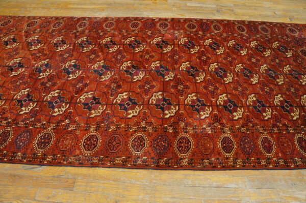 Terracotta rug featuring repeating navy blue and cream geometric medallions on light plank wood floor.