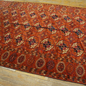 Red geometric rug with repeating navy and cream medallions fills the frame over light hardwood.