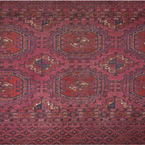 Deep red geometric rug featuring repeating navy and tan medallions and multiple ornate borders.