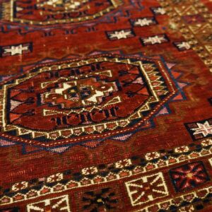 A close-up shows a deep red geometric rug with a large central octagonal medallion and patterned borders.
