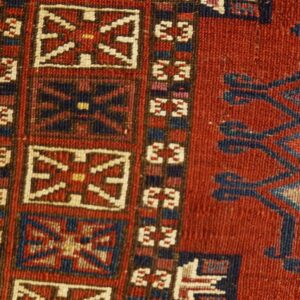 Geometric rug detail showing repeating medallions and angular motifs in red, navy, blue, and cream.