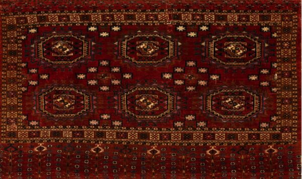 A deep red geometric rug featuring large, repeating octagonal medallions and multiple detailed borders.