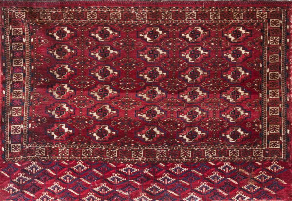 Dark red rug with repeating geometric medallions in navy, tan, and secondary patterned border designs.