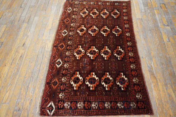 Traditional low-pile rug in deep red, orange, and navy geometric patterns on distressed wood planks.