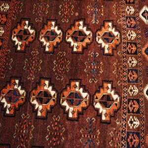 Geometric rug in deep red, orange, navy, and cream with a high pile lying on light hardwood planks.