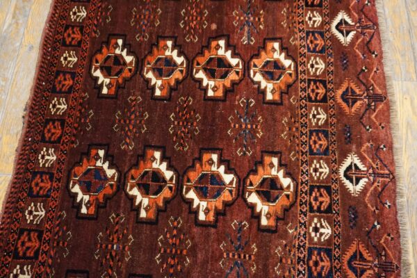 Geometric rug in deep red, orange, navy, and cream with a high pile lying on light hardwood planks.